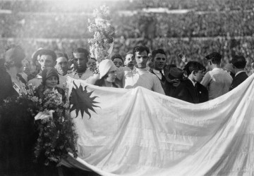 Uruguayan goalkeeper Enrique Ballesteros (centre) holding a bouquet of flowers as the team, fans, and officials line up behind the national flag during the celebrations at the end of the World Cup Final.