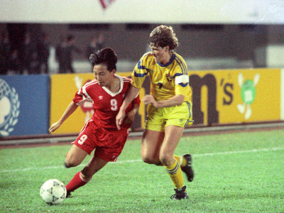 China's Sun Wen (left) runs a ball against a Swedish opponent.