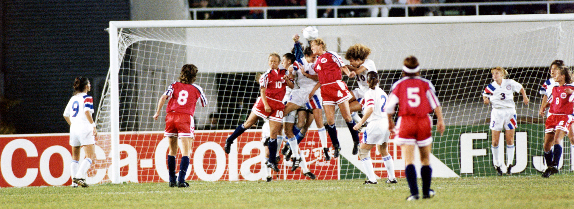 Players of both teams, Norway and the USA, are seen fighting for a high ball in the USA penalty area during the World Cup Final.