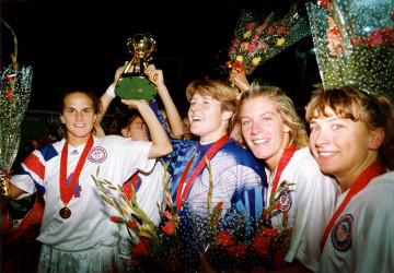 Members of the US Women's National Soccer Team with their gold medals and the trophy.