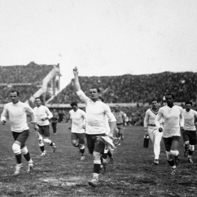 Uruguay captain Jose Nasazzi (arm raised) leads his team on a lap of honour after their 4-0 victory in the match against Romania, securing Uruguay's place in the semi-final.